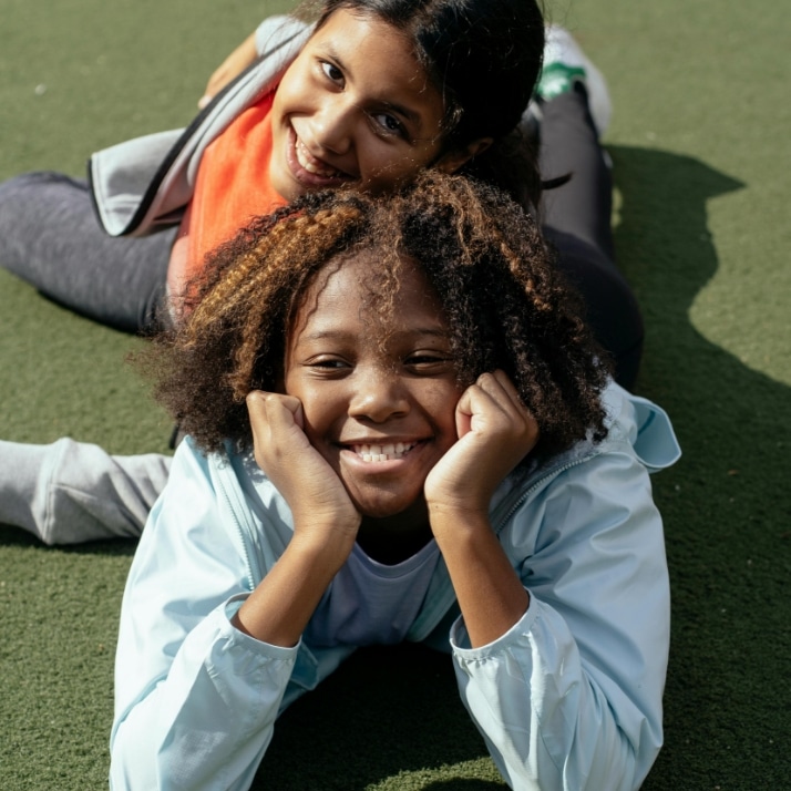 2 kids hanging out laying down on the grass